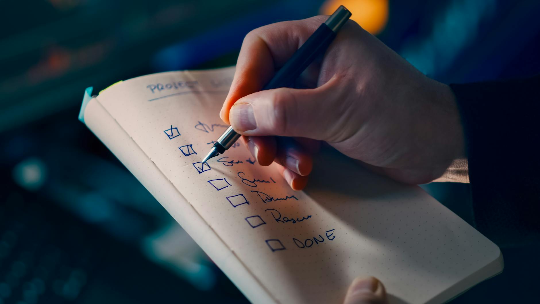 Brand audit checklist — diagnosis on paper Close-up of a hand writing a checklist in a notebook, symbolising productivity and organisation.