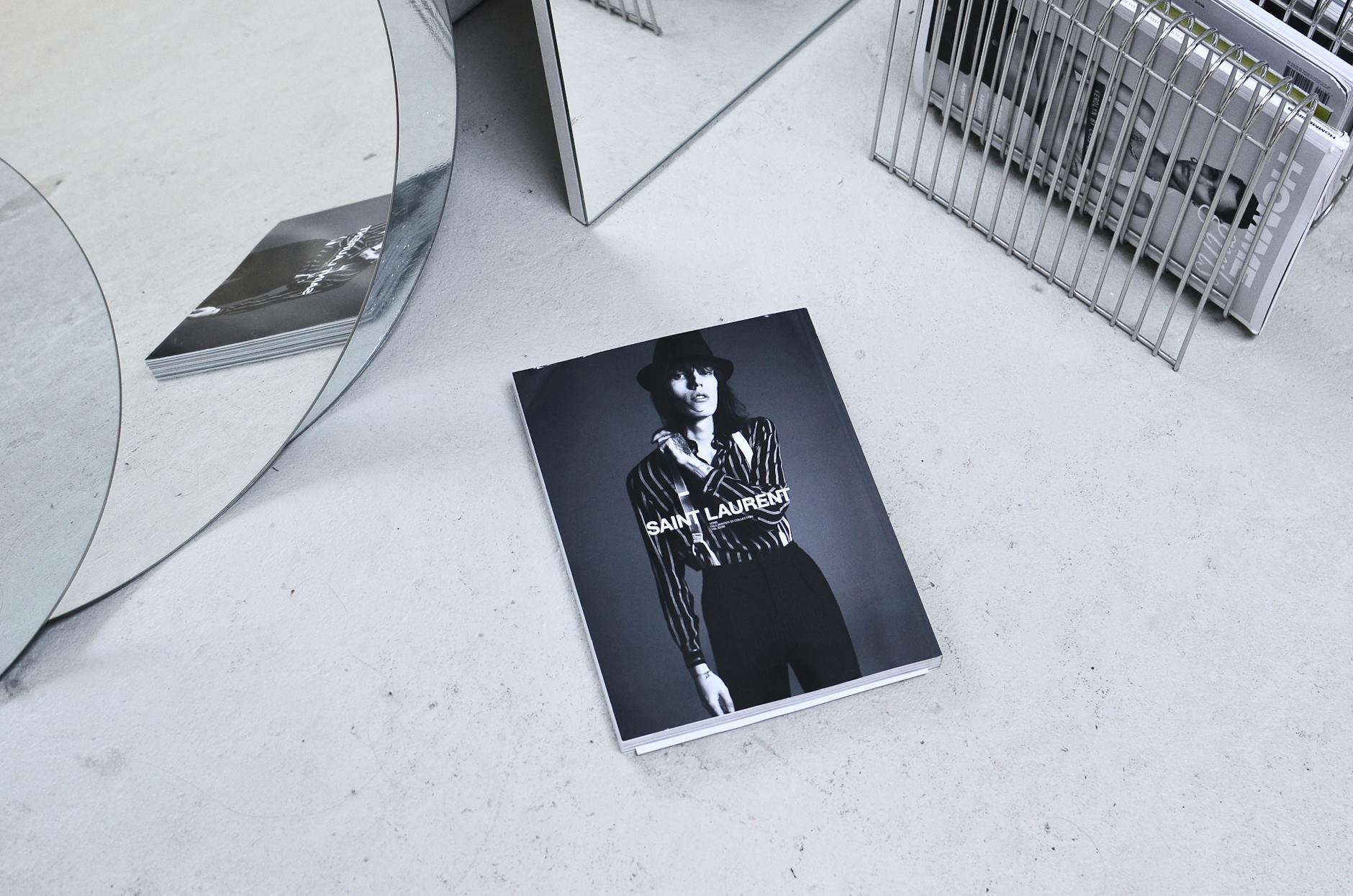 Black and white high angle fashion magazine placed on table and reflecting in geometrical mirrors and a rack with journals.