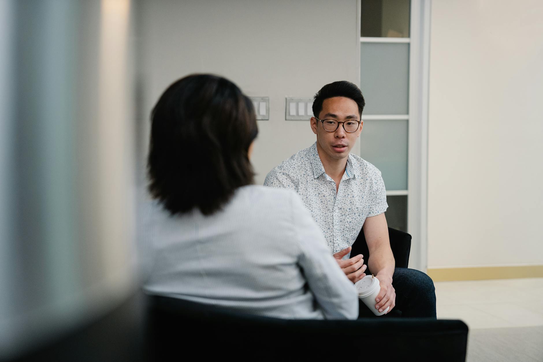 Two colleagues having a focused conversation in an office setting — the qualitative work behind positioning.