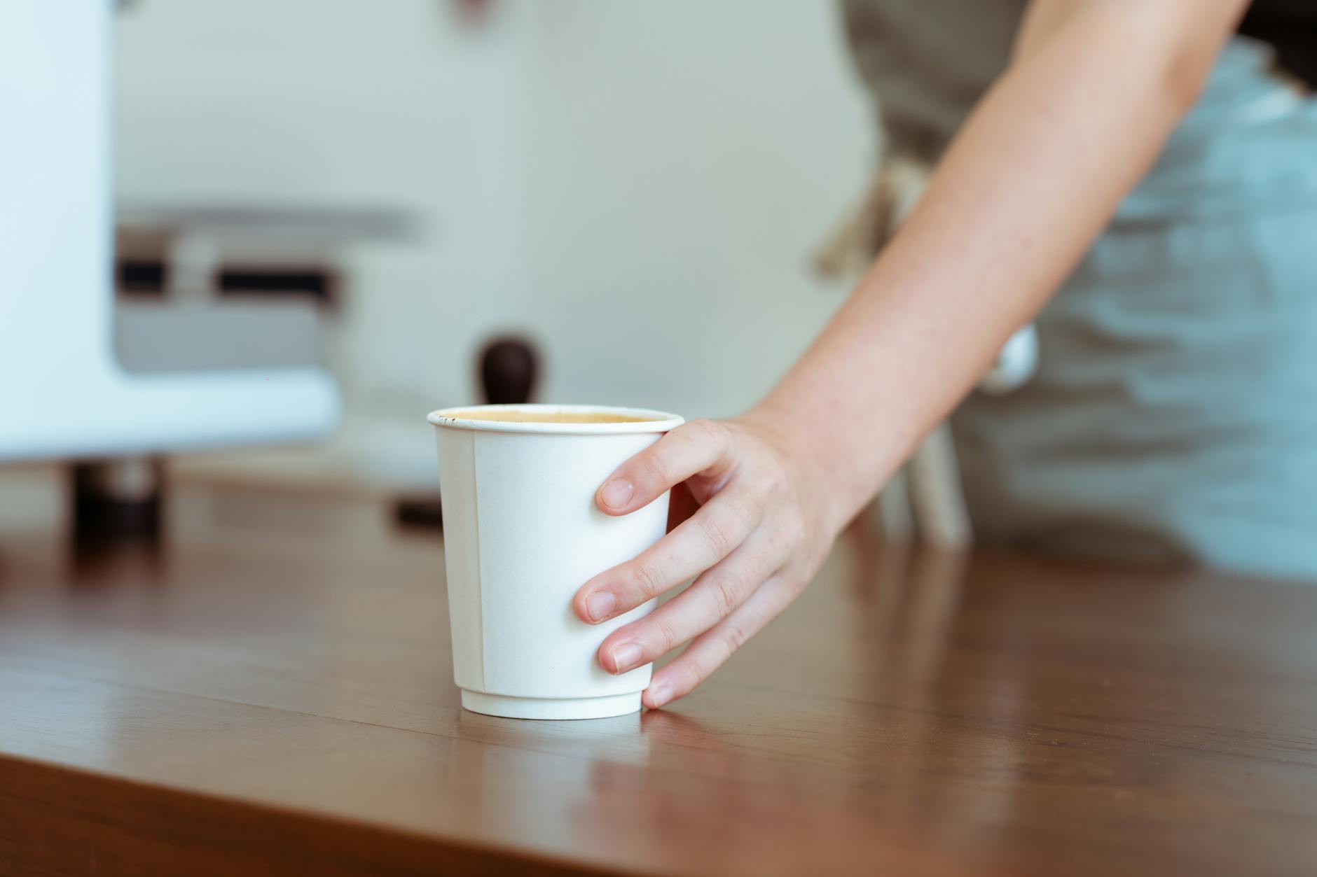 The brand-ops gap — featured image A hand serving a cup at a hospitality counter — illustrating the brand operations gap where brand expression meets the service desk.