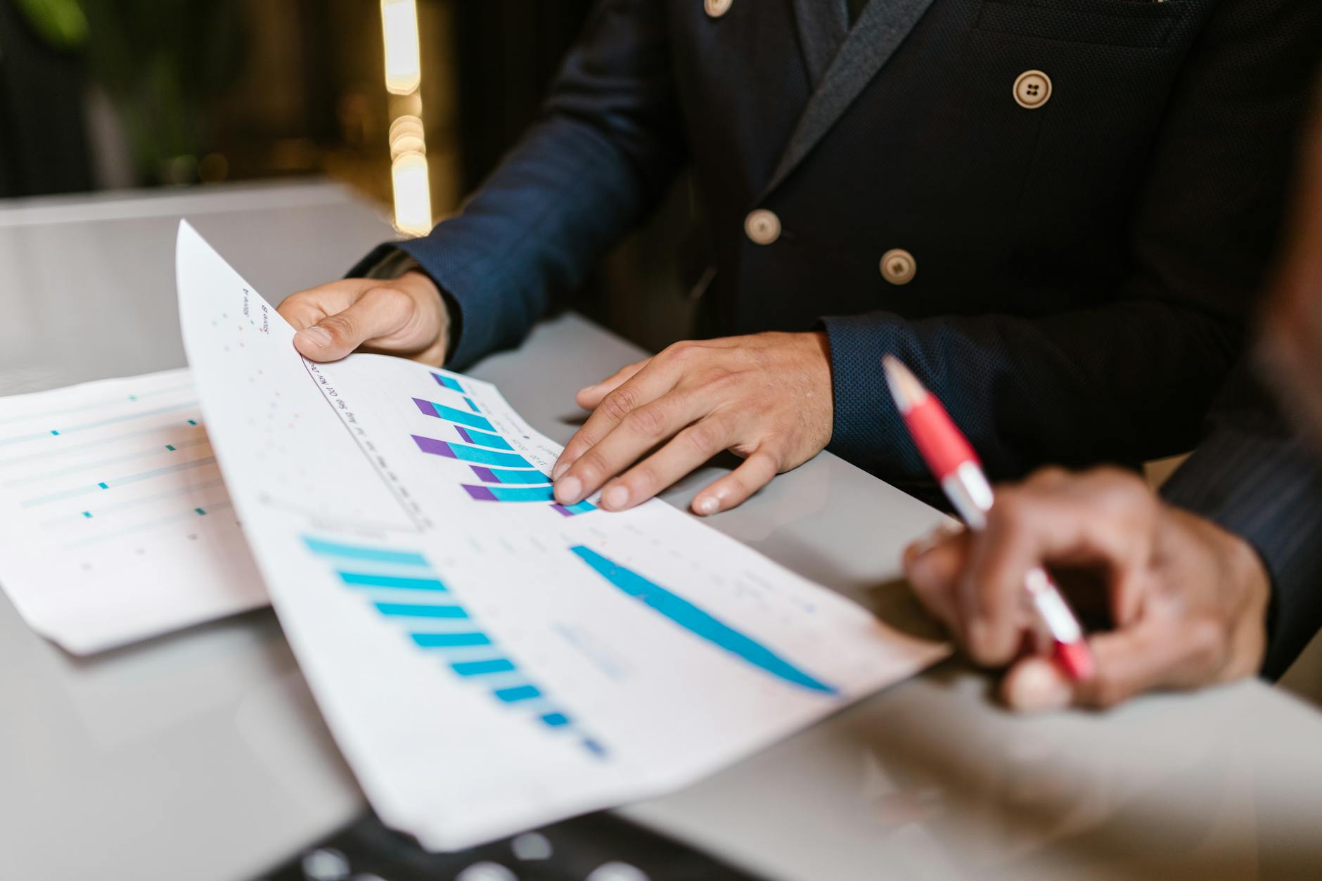 Close-up of professionals reviewing performance graphs at a business meeting.
