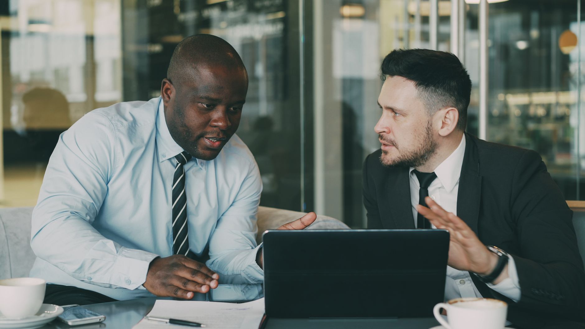 Co-founder disagreement on brand direction Two professionals discussing strategy with a laptop in an office.