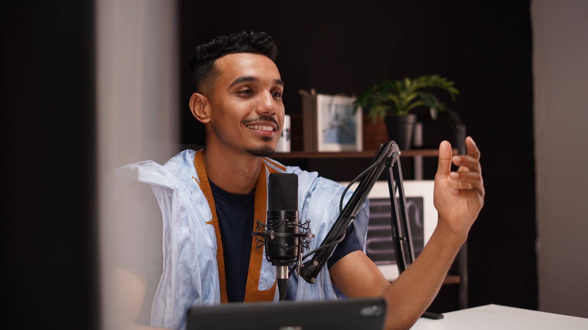 A person recording a podcast in a home studio with a professional microphone.
