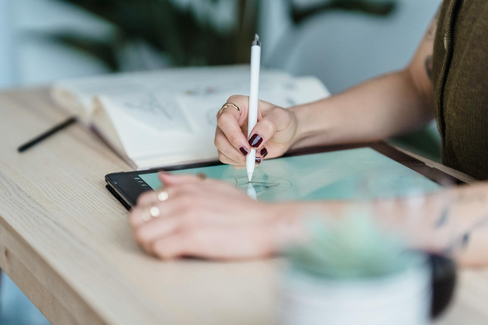 Logo evolution — refresh vs redraw Designer using a tablet and stylus to draw logo sketches at a wooden desk.