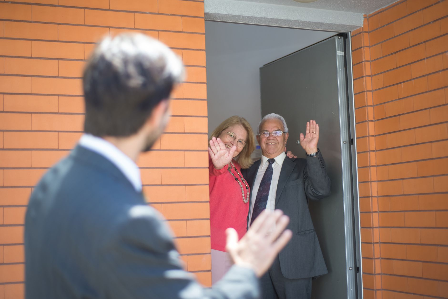 Onboarding as a brand moment A person welcomed at a home entrance, waving, with another figure in the foreground.